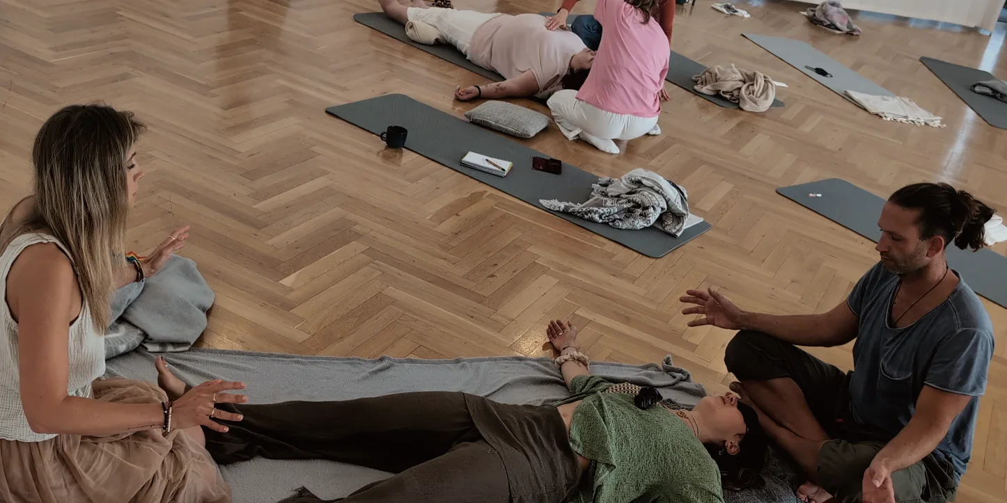 Teilnehmerin auf einer Matte, begleitet von zwei Facilitatorinnen und einem Facilitator